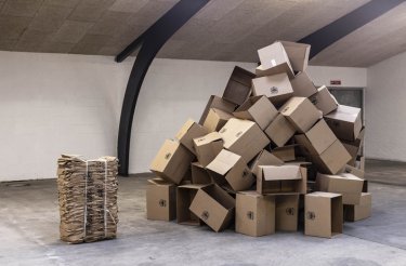 Empty warehouse with a compressed cardboard bale on the left and a large stack of loose cardboard boxes on the right