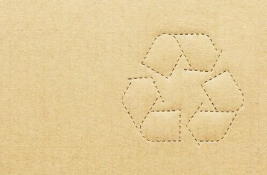 Close-up of cardboard with a recycling symbol punched into it