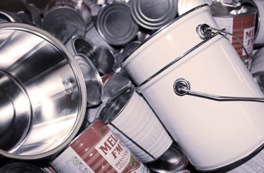 empty cans in a pile with one big white can in front