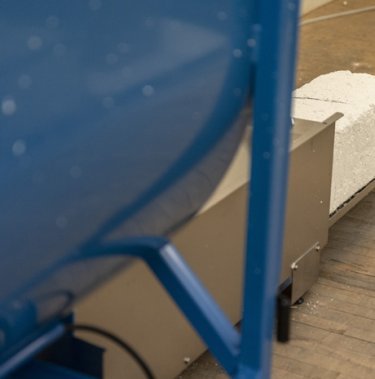 recycled polystyrene coming out in block from a blue compactor