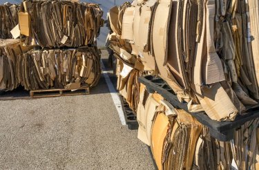 bales from a recycling baler in stacks on asphalt