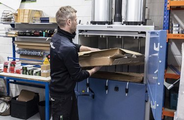 man putting cardboard in a baler on free trial