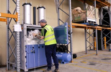 man puts soft plastic in recycling baler